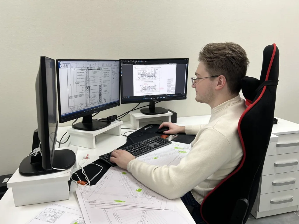 Steel detailer working on shop and erection drawings at dual monitors